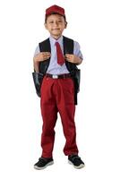 A Indonesian boy in a red school uniform and cap, smiling and carrying a black backpack. Ready for school photo