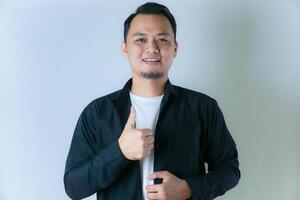 A man in a black shirt gives a thumbs-up, exuding confidence and positivity against a clean white background. photo