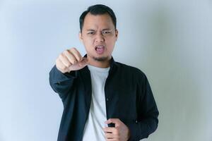 A man in a black shirt and white t-shirt yells while thrusting his fist forward, expressing determination or aggression against a plain background. photo