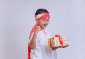 A boy dressed in white with a red and white flag on his back, celebrating with a gift in hand, expressing joy and excitement. photo