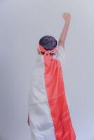 A child wearing a red-and-white robe, raising a fist, shows pride and enthusiasm. photo