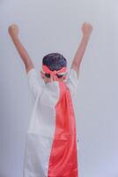 A child wearing a red-and-white robe, raising a fist, shows pride and enthusiasm. photo