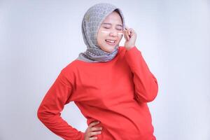 A woman in a red top and patterned hijab, smiling with closed eyes and expressing joy, embodies the concept of celebrating Indonesia Independence Day. photo
