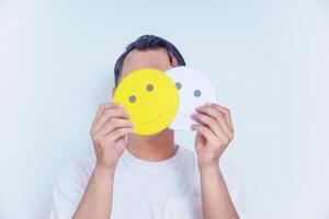 A person holds two facial expression cards, one happy and one neutral, symbolizing emotions and choices. world mental health day concept photo