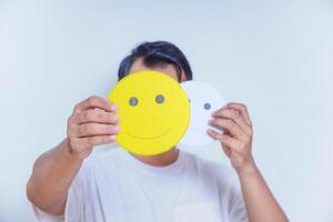 A person holds two facial expression cards, one happy and one neutral, symbolizing emotions and choices. world mental health day concept photo