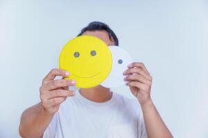 A person holds two facial expression cards, one happy and one neutral, symbolizing emotions and choices. world mental health day concept photo