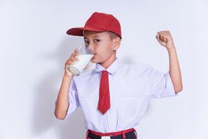 A confident boy in a red cap enjoys a glass of milk, promoting strength and health with a triumphant pose. photo