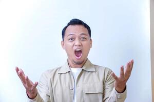 A surprised man expressing excitement and shock with wide open mouth and raised hands. photo