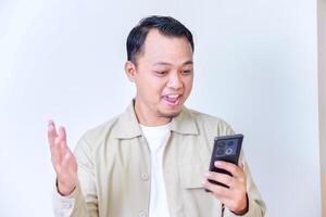 A surprised man expressing excitement and shock while hold smartphone and raised hands. photo