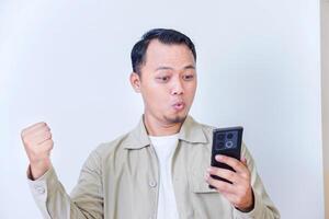 A surprised man expressing excitement and shock while hold smartphone and raised hands. photo
