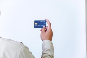 A hand holding a modern credit card with a microchip against a plain background. photo