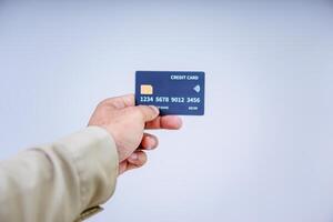 A hand holding a modern credit card with a microchip against a plain background. photo