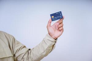 A hand holding a modern credit card with a microchip against a plain background. photo