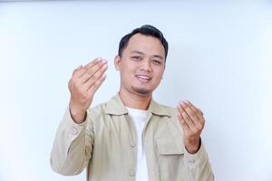 A smiling man with an inviting gesture, wearing a beige jacket against a light background. photo
