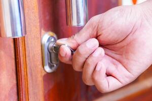 A hand using a key to unlock a wooden door, symbolizing security and access. photo