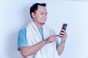 A man in a towel smiles while using his smartphone, enjoying a relaxed moment. photo