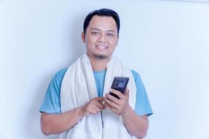 A man in a towel smiles while using his smartphone, enjoying a relaxed moment. photo