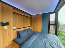 Modern bedroom with large window overlooking misty green landscape. photo