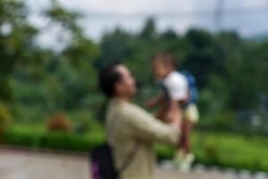 Blurred of A joyful moment between a Asian father and his smiling daughter in a beautiful green park. concept of fater's day photo