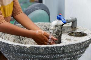 Hands are being washed at the stone sink with running water for cleanliness and hygiene. photo