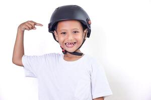 A confident asian boy wearing a helmet, pointing to his helmet with a big smile. photo