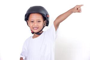 A cheerful asian boy in a helmet points upwards with a bright smile. photo