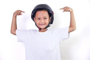 A confident asian boy wearing a helmet, pointing to his helmet with a big smile. photo