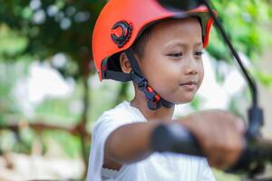 A happy asian boy in a bright helmet poses confidently on a electric scooter photo