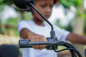 selective focies, A asian child prepares to ride a electric bike, gripping the handlebars tightly, focused, and determined. photo