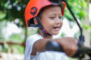 A happy asian boy in a bright helmet poses confidently on a electric scooter photo