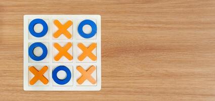 A game of Tic-Tac-To on a wooden table for fun entertainment. photo
