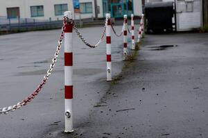 Chain-linked posts line a wet surface in an empty parking area photo