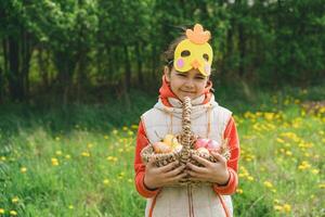 Girl with eggs basket and with a chicken mask on Easter egg hunt photo