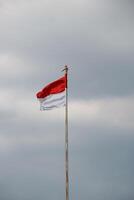 Indonesian flag fluttering in the wind with dark clouds in the background. photo