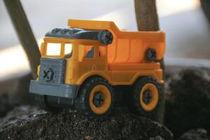Children's toy colored small truck on the grass background of sand and stones loaded with cargo photo