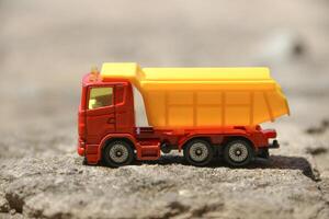 Children's toy colored small truck on the grass background of sand and stones loaded with cargo photo