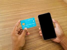 Hands Holding Credit Card and Smartphone on Wooden Table photo