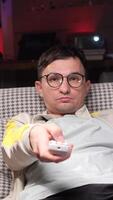 vertical Man using remote control while relaxing on armchair at home video