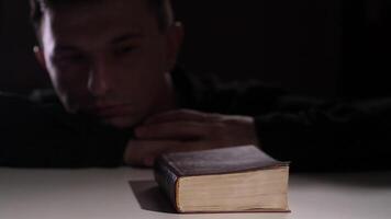 Priest resting his head on hands near holy bible after praying video