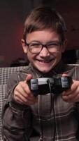 vertical happy boy with glasses plays games with a gamepad. Boy dances and rejoices video
