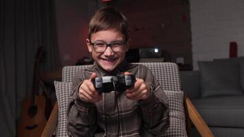 happy boy with glasses plays games with a gamepad. Boy dances and rejoices video