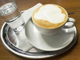 Cappuccino with foam and sparkling water on silver tray photo