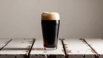 A dark beer is sitting on top of a wooden table photo