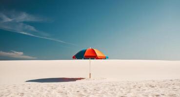 An orange and blue umbrella stands in the middle of a white sand beach photo