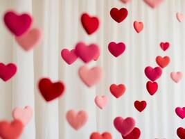 A bunch of red and pink hearts are hanging from a curtain photo