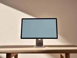 A computer monitor on a wooden table in front of a wall photo