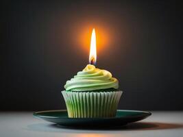 A cupcake with a green frosting and a lit candle photo