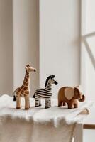 A wooden toy giraffe, zebra and elephant on a table photo