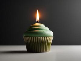 A green cupcake with a single candle on top photo