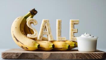 Creative banana display spelling sale on a wooden board with yogurt on the side photo
